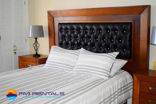 a bed with a black padded headboard and white pillows at Marina Pinacate B-408 in Puerto Peñasco