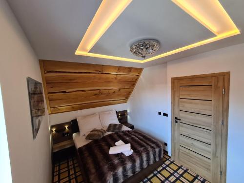 a bedroom with a bed and a wooden ceiling at Royal House in Zakopane