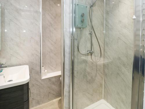 a shower with a glass door next to a sink at Sunny View in Dawlish