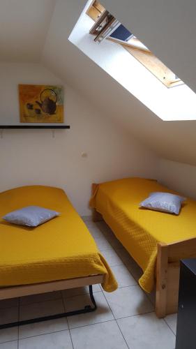two beds in a room with yellow sheets at résidence lac de La Sole T3 4 pers les minimes avec piscine in La Rochelle