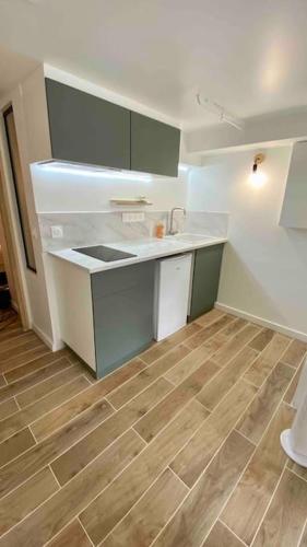 Il comprend une cuisine avec des comptoirs blancs et du parquet. dans l'établissement Appartement charmant proche de Paris, à Villemomble