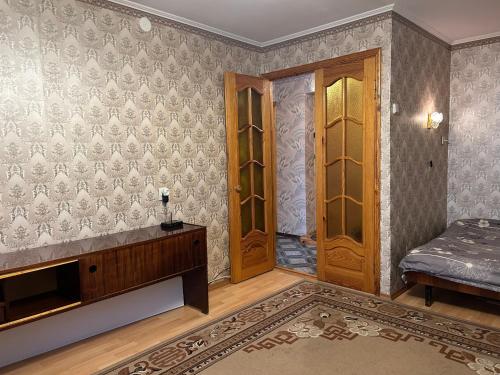 an empty room with a bed and two wooden doors at Недорога квартира на Харківській, 32 in Sumy