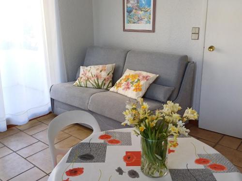 un salon avec un canapé et une table avec des fleurs dans l'établissement Studio Antares-1 by Interhome, à Cavalaire-sur-Mer