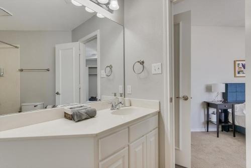 Baño blanco con lavabo y espejo grande en Glamorous 4Br Home with Pool Hot Tub & Grill en Carrollton
