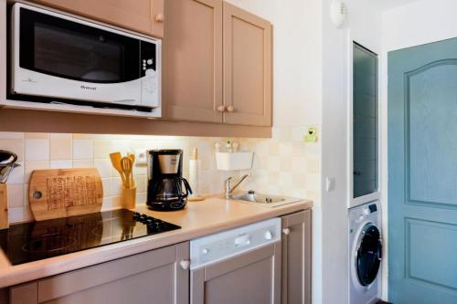 une cuisine avec un micro-ondes et une cuisinière four supérieur dans l'établissement Résidence La Marelle et Le Rami - maeva Home - 2 pièces 5 Personnes Prestige MAE-9396, à La Plagne Tarentaise