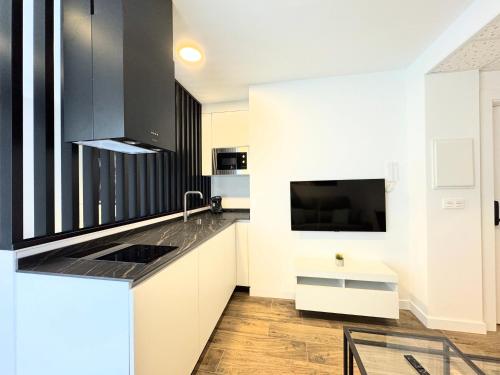 kuchnia z białymi szafkami, zlewem i telewizorem w obiekcie Apartamentos Mk77 - Identia Sport w mieście León