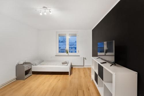 biała sypialnia z łóżkiem i oknem w obiekcie Moderne Wohnung mit Garten & Küche w mieście Celle