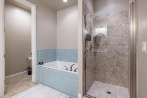 a bathroom with a tub and a shower with blue tiles at Luxury At The Ledges in St. George