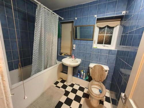 Baño de azulejos azules con aseo y lavamanos en Double Bedroom WA Greater Manchester en Middleton