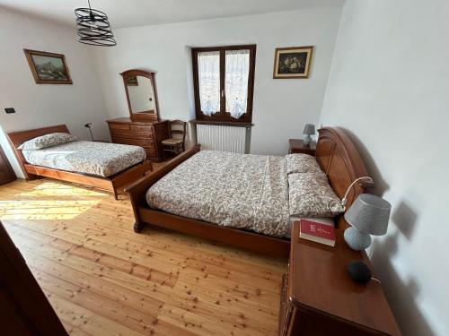 Bagnolo PiemonteにあるCasa Saladaのベッドルーム1室(ベッド2台、ドレッサー、鏡付)