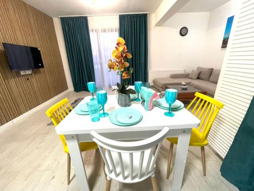 a living room with a white table and yellow chairs at Residence 3 in Ploieşti