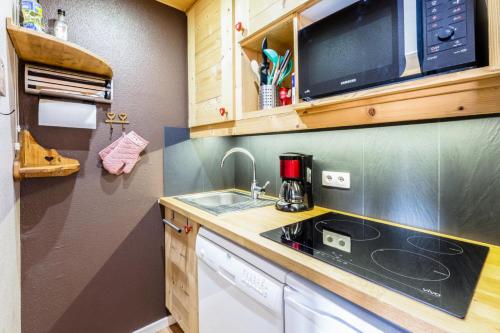 une petite cuisine avec un évier et un micro-ondes dans l'établissement Résidence L'Ours Blanc - maeva Home - 2 Pièces 4 Personnes Sélection MAE-3817, à Huez