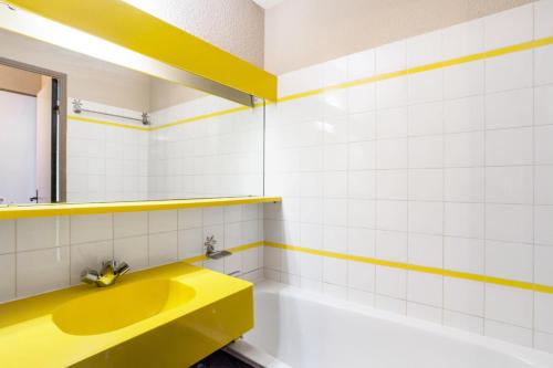 La salle de bains est pourvue d'un lavabo jaune et d'une baignoire. dans l'établissement Résidence Le Hameau du Sauget - maeva Home - 2 Pièces 4 Personnes Sélection MAE-3989, à La Plagne Tarentaise