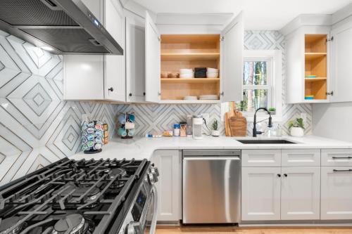 a kitchen with white cabinets and a stove top oven at Outdoor Projector, Arcade, Fire Pit, 2 Car Garage, 2 Living Rooms in Snellville