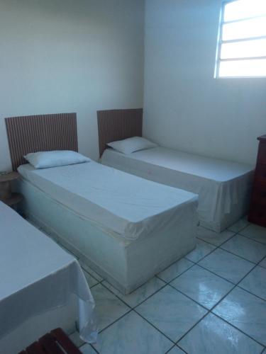2 camas en una habitación con ventana en Egbirin Pousada en Ilhéus