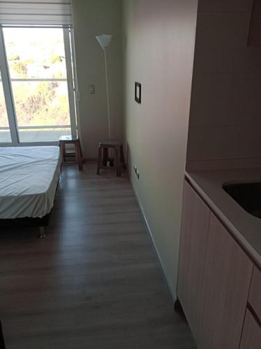 a room with a bed and a kitchen with a window at Departamento nuevo cerro placeres in Viña del Mar