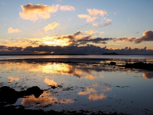 a reflection of the clouds in the water at sunset at Taigh Gorm in Balivanich