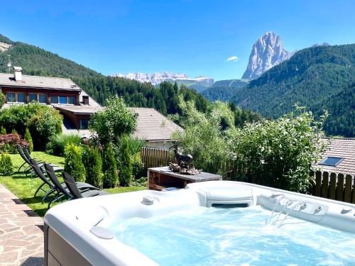 a hot tub in a backyard with a view of mountains at Chalet Bernardi Apartments in Ortisei