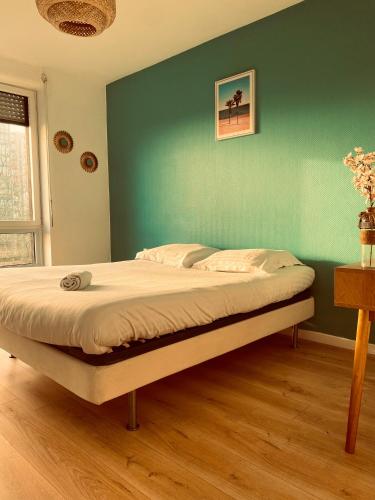Ce lit se trouve dans une chambre dotée d'un mur vert. dans l'établissement Spacieux appartement lumineux, à Brest