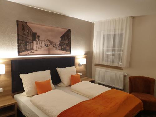 Schlafzimmer mit einem Bett mit orangefarbenen und weißen Kissen in der Unterkunft Gasthof Bräuhaus Lepple in Vöhringen