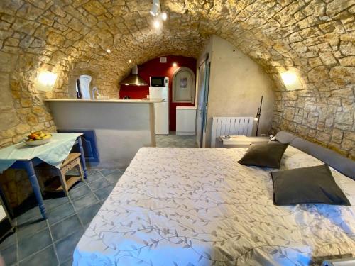 1 dormitorio con 1 cama grande en una pared de piedra en L’Écrin de Gilette, en Gilette