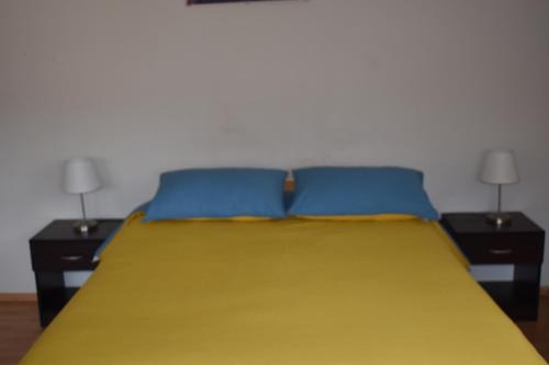 a bed with two blue pillows and two tables at saga andina in Cusco
