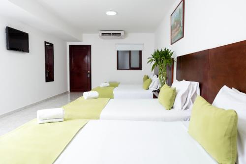 2 camas en una habitación con almohadas blancas y verdes en Hotel Granada Real, en Cali
