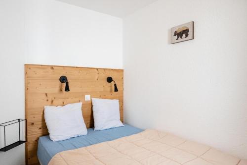 une chambre avec un lit avec une tête de lit en bois dans l'établissement Résidence Les Constellations - maeva Home - 2 Pièces 5 personnes Sélection MAE-7324, à La Plagne Tarentaise