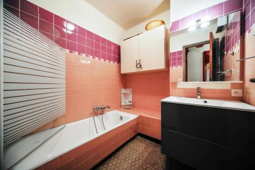 y baño con azulejos rosas, bañera y lavamanos. en Appartement 2 pièces 6 personnes avec superbe vue - maeva Home 82240, en Font-Romeu-Odeillo-Via