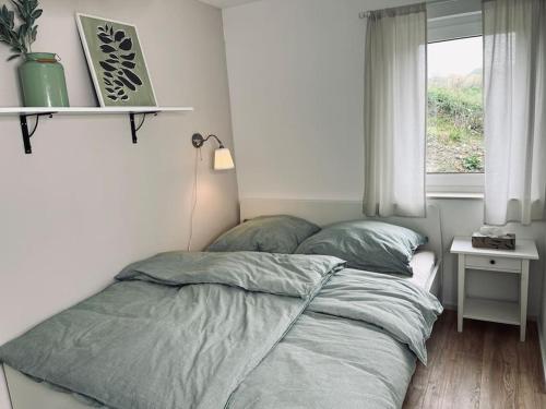 - une chambre avec un lit avec deux oreillers et une fenêtre dans l'établissement Kuscheliges Apartment am Limes, à Rainau