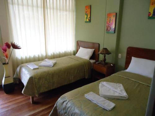 a hotel room with two beds and a window at Killaqente in Cusco