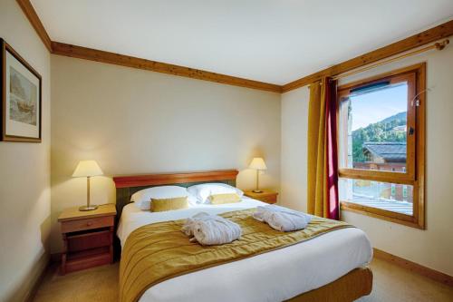 une chambre avec un grand lit et une grande fenêtre dans l'établissement Résidence Les Arcs 1950 Le Village - maeva Home - 2 pièces 4 personnes Sélection MAE-9500, à Bourg-Saint-Maurice