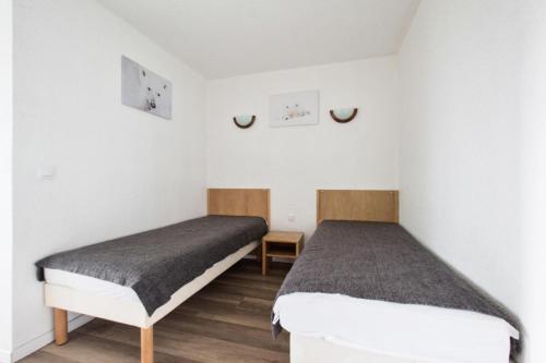 deux lits dans une chambre aux murs blancs et au parquet dans l'établissement Résidence Les Bergers - maeva Home - Studio 4 personnes - Confort MAE-9591, à Huez