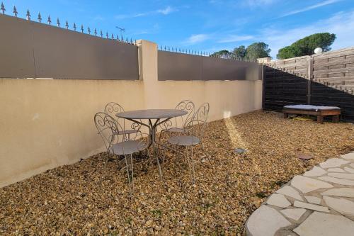 d'une terrasse avec une table et des chaises à côté d'un mur. dans l'établissement Studio in quiet residence with pool, à Fréjus