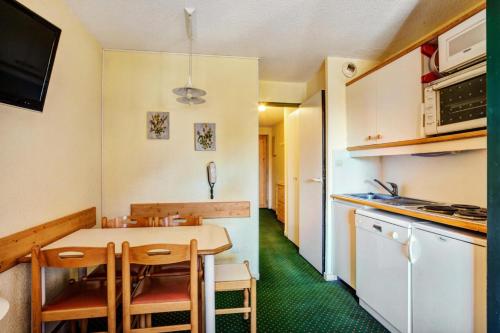 une petite cuisine avec une table et des chaises dans l'établissement Résidence Le Hameau du Sauget - maeva Home - 2 Pièces 4 Personnes Confort MAE-9861, à La Plagne Tarentaise