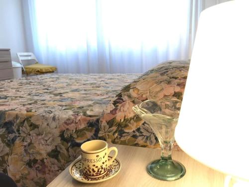 a table with a cup and a glass on a bed at Three rooms close to the sea and services in Riva Trigoso