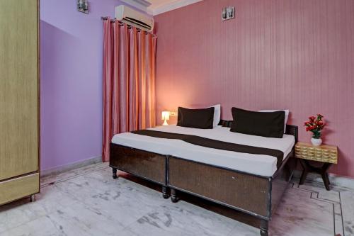 ein Schlafzimmer mit einem großen Bett in einer rosa Wand in der Unterkunft OYO Hotel Galaxy?s Inn in Gurgaon