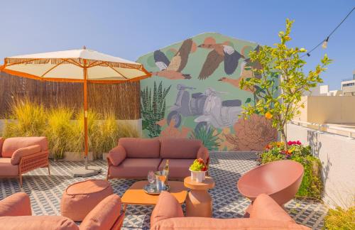 eine Terrasse mit Sofas, einem Regenschirm und einem Wandbild in der Unterkunft Albi Florentin in Tel Aviv