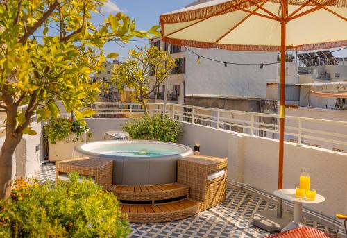 a balcony with a hot tub and chairs and an umbrella at Albi Florentin - Traveler's Choice 2024 in Tel Aviv