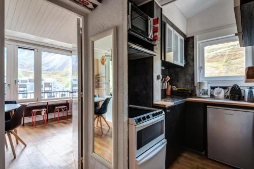 Il comprend une cuisine équipée d'une cuisinière. four supérieur à côté d'une table dans l'établissement Appartement à Tignes avec accès direct aux pistes - Appartement 2 pièces 6 personnes Sélection MAE-1191, à Tignes