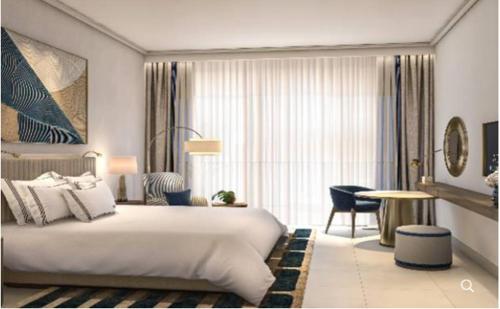 um quarto de hotel com uma cama grande e uma mesa em Address Beach Resort Marassi em El Alamein