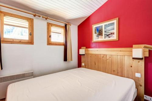 - une chambre avec un lit blanc et des murs rouges dans l'établissement Résidence La Marelle et Le Rami - maeva Home - Appartement 3 pièces 7 perso 20, à La Plagne Tarentaise