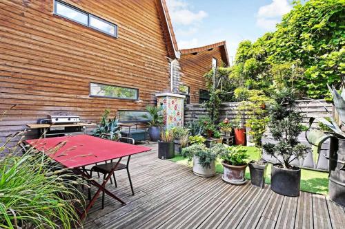 une terrasse avec une table rouge et des plantes en pot dans l'établissement Loft d'artiste, exceptionnel., à La Courneuve