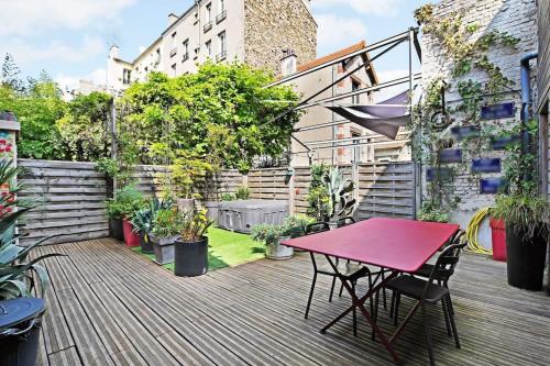 une terrasse en bois avec une table rouge et des chaises. dans l'établissement Loft d'artiste, exceptionnel., à La Courneuve