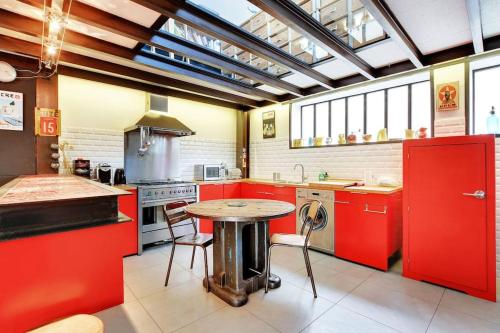 een keuken met rode kasten en een tafel erin bij Loft d'artiste, exceptionnel. in La Courneuve