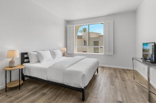 a white bedroom with a large bed and a window at Modern & Uncluttered - A Ryson Property in Palm Springs