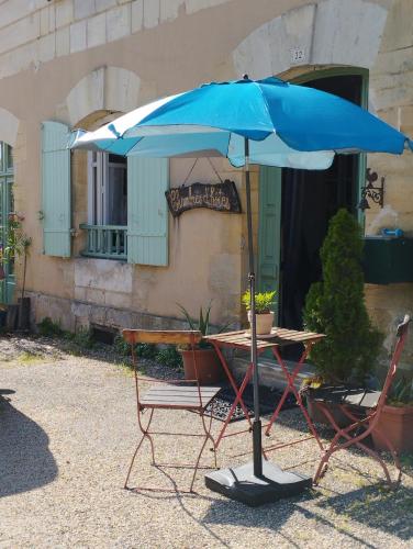 une table et des chaises avec un parasol en face d'un bâtiment dans l'établissement Aux chambres du bourg, à Saint-Avit-Sénieur