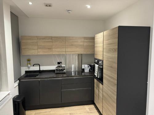 a kitchen with wooden cabinets and a black counter top at Apartology Manchester in Manchester