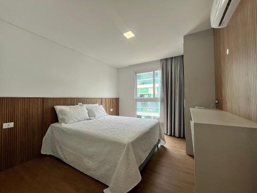 B235 - Apartamento com 02 suítes novo em Bombinhas في بومبينهاس: غرفة نوم بسرير كبير ونافذة