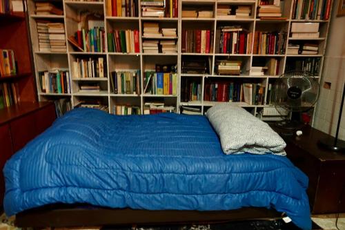 a bed with a blue comforter in a room with book shelves at Encantadora casa de piedra in Guatavita